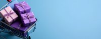 Pink and purple gift boxes with polka dot ribbons stacked on blue background with copy space, festive holiday celebration arrangement for special occasions.