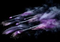 Makeup brushes with explosive purple powder and smoke effect against black background, creating dynamic motion and artistic cosmetic splash photography.