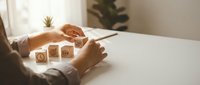 Hands arranging wooden cubes with business strategy icons on a desk, symbolizing planning, goal setting, and organizational management.