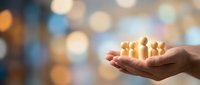 Young adult male hand holding glowing golden figures representing people, symbolizing teamwork, community support, and human connection for business and social concepts.