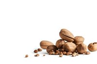 Mixed whole nuts including walnuts, hazelnuts and pine nuts scattered on white background, isolated composition for food packaging and healthy eating concepts.