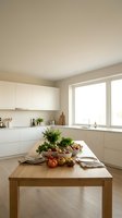 Modern minimalist kitchen interior with wooden island featuring fresh vegetables and herbs for healthy cooking and meal preparation.