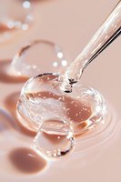 Clear liquid drops forming heart shapes on pink background with water surface tension creating delicate reflections and light effects. Macro photography.