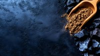 Aromatic cocoa powder in wooden scoop on dark textured background with dramatic lighting and copy space for food photography and culinary designs.