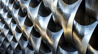 Metallic architectural detail with curved geometric pattern creating dramatic light and shadow play. Modern building exterior featuring repetitive sculptural elements.