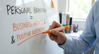 Professional businessman writing personal branding strategy on whiteboard showing business growth and positive reputation concepts in modern office.