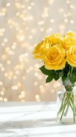 Yellow roses in glass vase on marble surface with golden bokeh lights background for romantic occasions and home decor.