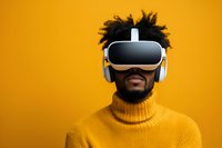 Young African American man wearing virtual reality headset and white headphones, smiling while experiencing VR technology against vibrant yellow background.