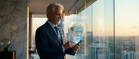 Senior businessman in suit interacting with holographic AI technology interface in modern office with city skyline view at sunset.