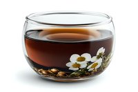 Glass bowl with dark herbal tea and blooming white chamomile flowers floating on surface, decorative composition on white background, isolated beverage photography.