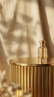 Luxury perfume bottle on a golden ribbed pedestal with soft linen backdrop and warm sunlight shadows for cosmetic advertising.