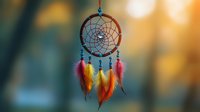 Colorful dreamcatcher with vibrant orange, yellow and pink feathers hanging outdoors against blurred bokeh background in warm sunset light. Perfect for spiritual designs.