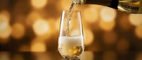 Pouring golden alcoholic beverage into glass against warm bokeh background, suitable for beverage advertising and hospitality marketing.