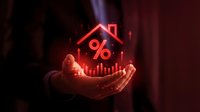 Businessman holding glowing red house with percentage symbol and upward arrow representing mortgage rates, real estate investment growth and property market trends.