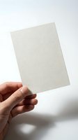 Hand holding blank textured paper card against white background for mockup design and branding presentation projects.