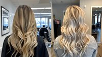 Blonde balayage hair with natural waves shown from back view in salon setting. Professional hair coloring technique demonstrates modern highlighting and styling results.