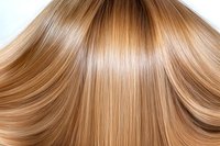 Smooth flowing honey blonde hair strands with natural highlights and shine, showcasing healthy straight hair texture and professional hair care results.