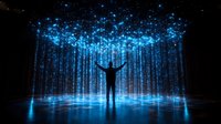 Silhouette of person with raised arms against magical blue light streams falling from above, creating ethereal atmosphere on reflective surface in dark space.