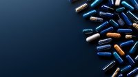 Medical capsules and pills scattered on dark blue background, pharmaceutical supplements in blue, white and gold colors for healthcare and medicine concepts.