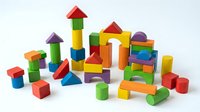 Colorful wooden building blocks set with geometric shapes including cubes, cylinders, triangles and rectangles arranged on white background for educational play.