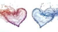 Two heart shapes formed by liquid splashes in contrasting red and blue colors against white background, creating dynamic fluid motion effect.