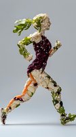 Creative food art composition showing running figure made from fresh vegetables and greens on light gray background, healthy lifestyle concept.
