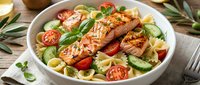 Grilled salmon fillet with fresh vegetables and pasta in white bowl, healthy meal for lunch or dinner preparation.