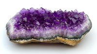 Purple amethyst crystal geode formation with deep violet crystalline interior and natural rough stone exterior showing mineral growth layers and formations.