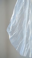 Flowing white sheer fabric with soft natural light creating elegant drapes and shadows against neutral background for textile and fashion design projects.
