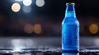 Cold blue glass bottle with water drops and condensation on dark background with blurred bokeh lights, fresh beverage concept for advertising and design.