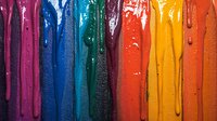 Vibrant multicolored paint drips flowing downward on dark surface create dramatic abstract pattern with water droplets and glossy texture for artistic background design.