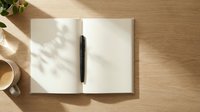 Open notebook with blank pages and black pen on wooden desk with natural sunlight casting shadows, suitable for business planning, journaling, and creative writing projects.