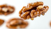 Fresh walnut kernels with golden honey drizzle on white background, organic healthy snacking and natural sweetener concept for culinary designs.
