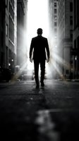 Silhouette of businessman walking down urban street towards bright light between tall buildings in dramatic black and white composition for corporate concepts.