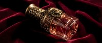 Elegant crystal perfume bottle with ornate golden cap resting on luxurious burgundy velvet fabric for beauty and fragrance advertising campaigns.