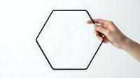 Hand holding pen drawing black hexagon outline on white background for business presentation and geometric design projects.