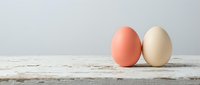 Two colored eggs on rustic wooden surface against neutral background for Easter celebration and spring holiday decoration concepts.