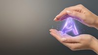 Hands protecting glowing letter A with magical particles and light effects on dark background for technology and innovation concepts.