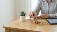 Professional businesswoman arranging wooden blocks with healthcare and medical icons on modern office desk for insurance planning and wellness concepts.