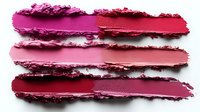 Smeared lipstick or cream blush samples in various pink and red shades on white background, showing texture and color gradients. Isolated cosmetic swatches.