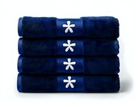 Stack of folded navy blue cotton bath towels with white flower embroidered labels, arranged neatly on white background for spa and bathroom decor.