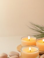 Glowing aromatherapy candles with zen stones and palm leaves on beige background. Spa wellness and meditation concept for relaxation and mindfulness.