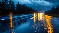 Dramatic rainy night on wet highway with glowing headlights reflecting on asphalt surface, moody dark forest silhouettes and stormy clouds creating atmospheric scene.