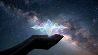 Glowing holographic sound wave floating above open palm against starry night sky with Milky Way galaxy backdrop for technology and music concepts.