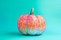 Festive pumpkin decorated with pink and gold glitter against turquoise background, modern holiday decor for autumn celebrations and seasonal displays.