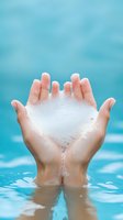 Cupped hands emerging from turquoise water holding white foam soap bubbles against bright blue background, symbolizing cleanliness, purity and personal care.