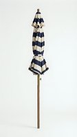 Closed striped patio umbrella with navy and cream horizontal stripes, wooden pole, and brass hardware on neutral background for outdoor furniture and garden design projects.