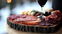 Gourmet charcuterie board with assorted cured meats, cheese, olives and red wine glass for elegant dining and entertaining occasions.
