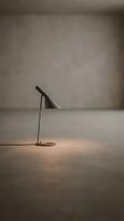 Minimalist desk lamp casting warm glow on concrete floor in empty studio space, contemporary interior design and modern lighting concept for home decor and workspace styling.