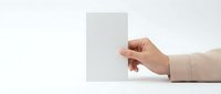 Female hand holding blank white card against clean background for business presentation and marketing materials.
